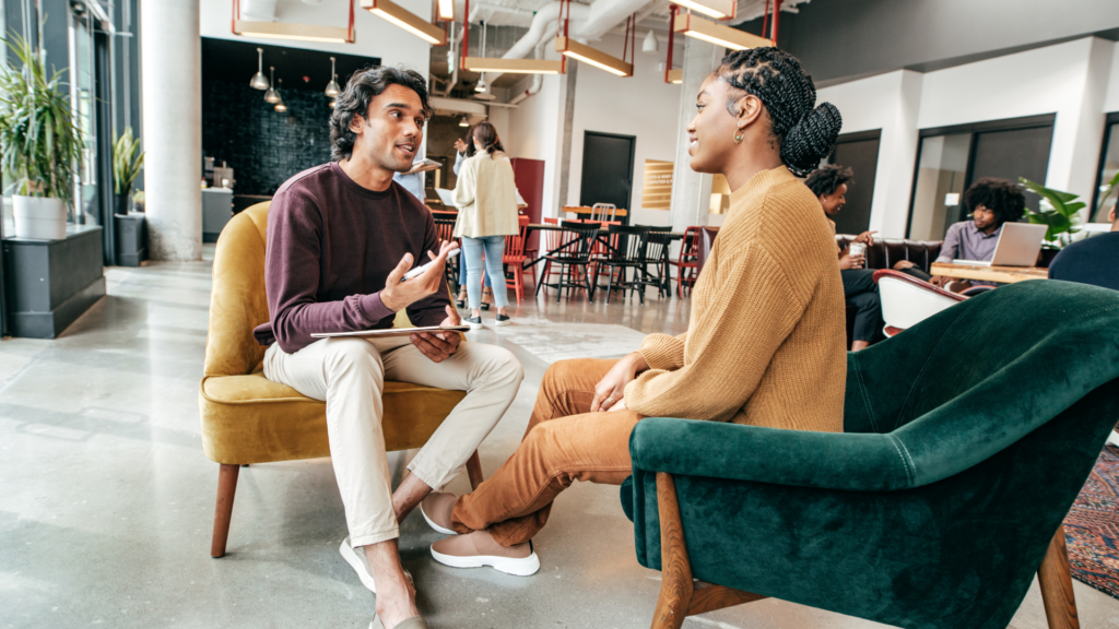 Artfully Media - Recruitment Advertising Made Simple Improve job advertising ROI without additional spend - LinkedIn Recruitment, a man and women sat having a discussion. Man has a notebook and pen in his hand