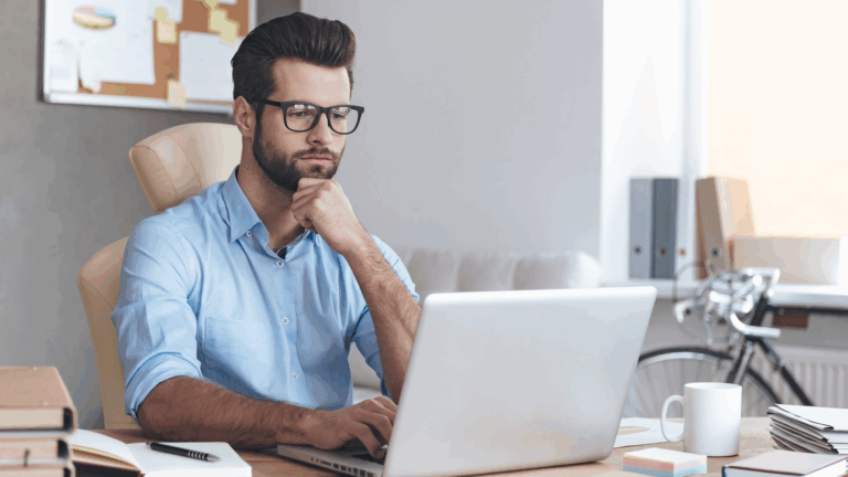 Artfully Media - Recruitment Advertising Made Simple Improve job advertising ROI without additional spend - Man thinking while working on a laptop sat at a desk.